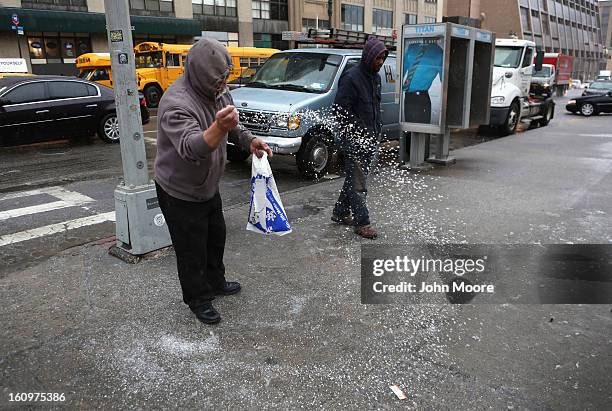 Man tosses salt on a slush-slick street as a major winter storm moves in on February 8, 2013 in New York City. Snow and freezing rain fell over...