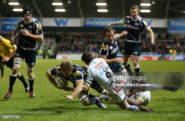 Dan Braid of Sale Sharks dives past a challenge from Will Chudley of Exeter Chiefs to score his try during the Aviva Premiership match between Sale...