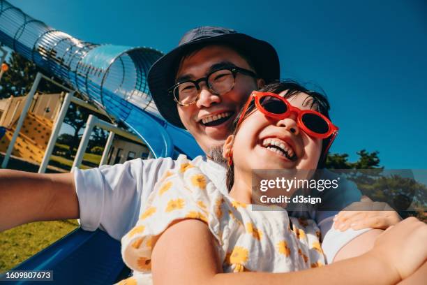 happy young asian father with her little daughter having fun playing on the tube slide together in an outdoor playground on a lovely sunny day. outdoor fun. happy childhood and fatherhood. father and daughter bonding moment. happy family life - 父の日　日本 ストックフォトと画像