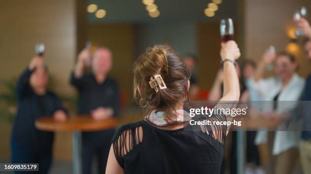 rear view of businesswoman giving small speech and toasting with collages during business party gathering - defocused stock pictures, royalty-free photos & images