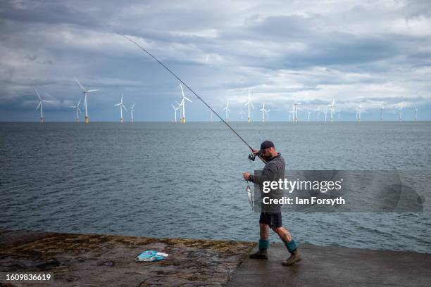 Fisherman lands a Mackerel as he fishes from the breakwater at South Gare on August 12, 2023 in Redcar, United Kingdom.