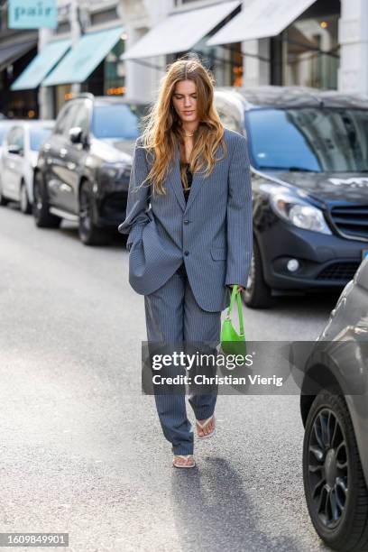 Lois Schindler wears grey oversized striped suit, green bag outside Rotate during the Copenhagen Fashion Week Spring/Summer 2024 on August 10, 2023...