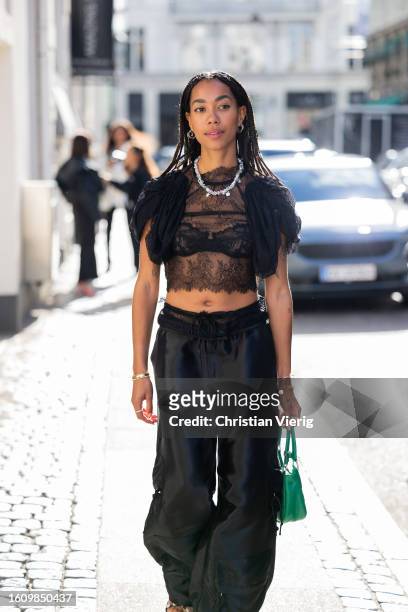 Amaka Hamelijnck wears laced top, necklace, black pants, green bag outside Rotate during the Copenhagen Fashion Week Spring/Summer 2024 on August 10,...