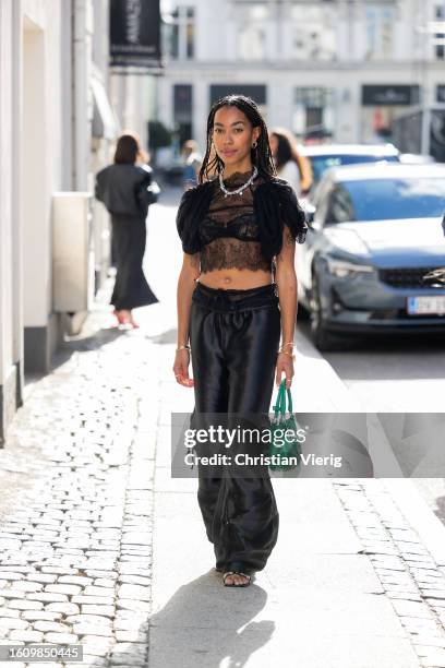 Amaka Hamelijnck wears laced top, necklace, black pants, green bag outside Rotate during the Copenhagen Fashion Week Spring/Summer 2024 on August 10,...