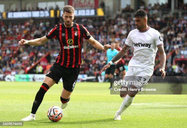 Chris Mepham of AFC Bournemouth runs with the ball whilst under pressure from Emerson Palmieri of West Ham United during the Premier League match...
