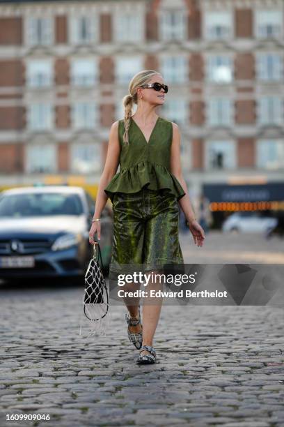 Guest wears brown marble print pattern sunglasses from Chanel, gold earrings, a green embossed pattern V-neck / sleeveless / ruffled top, khaki and...