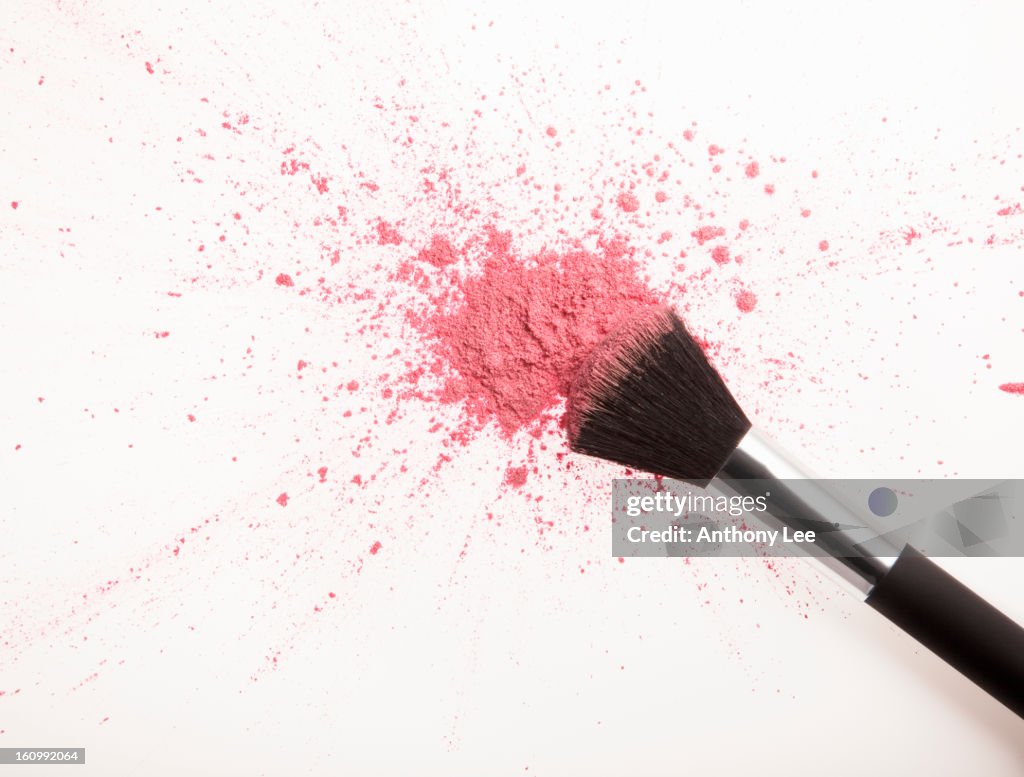 Makeup brush and pink blush powder splatter