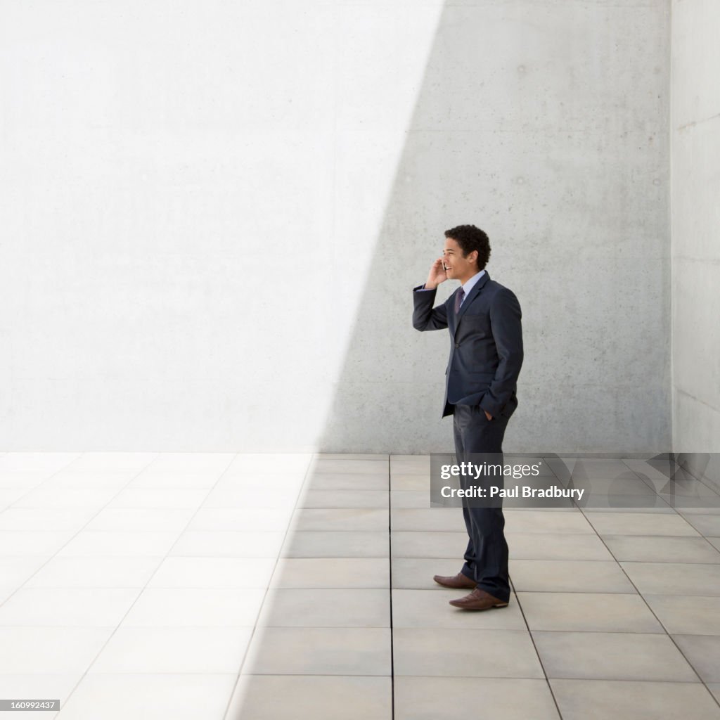 Businessman standing in shade and talking on cell phone