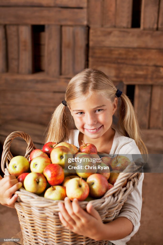Portrait of smiling girl holding bushel of apples