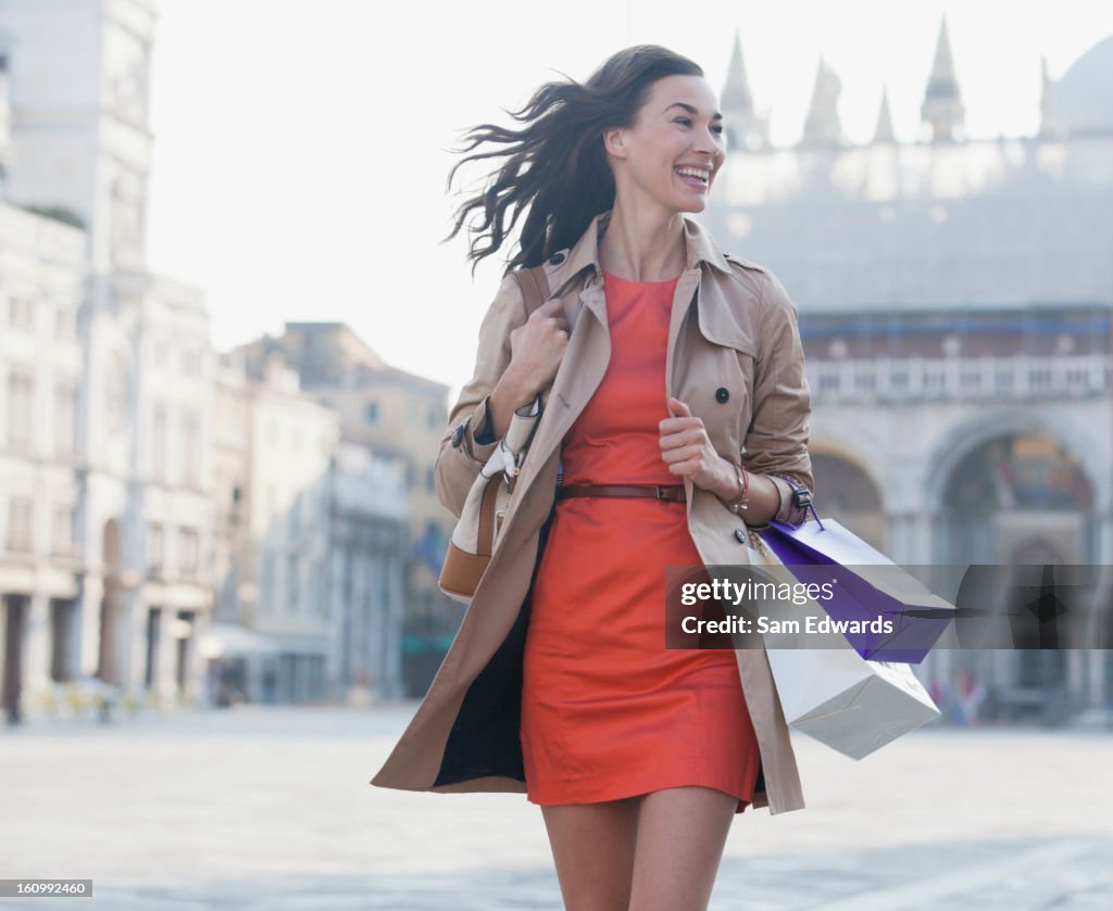 Mujer sonriente con bolsas de compras caminando en San Marcos