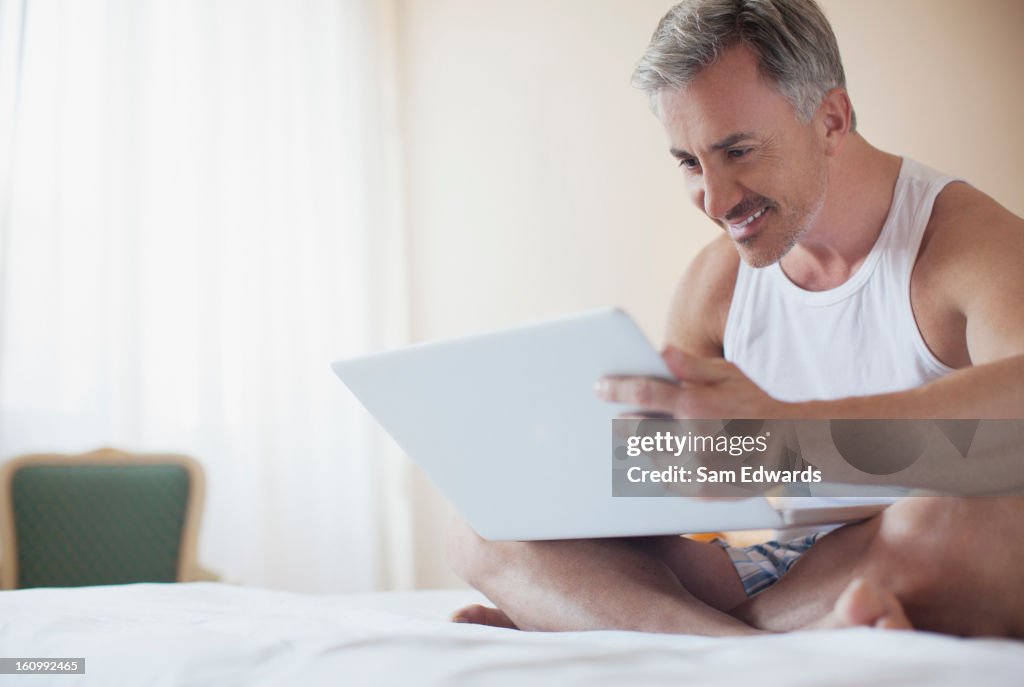 Lächelnd Mann mit laptop im Bett