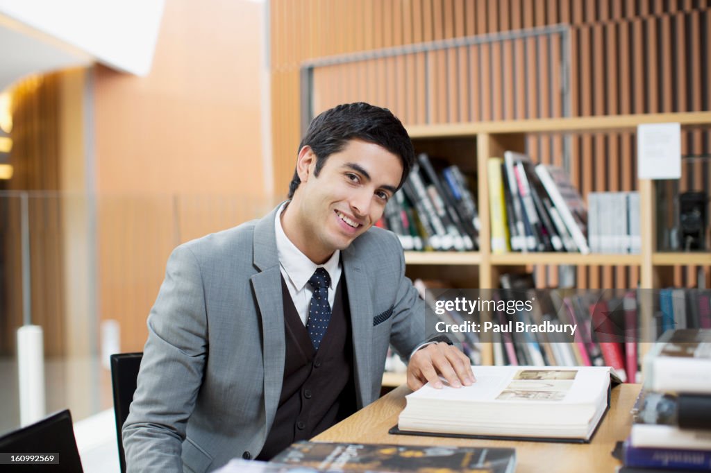 Portrait of smiling businessman reading book in library