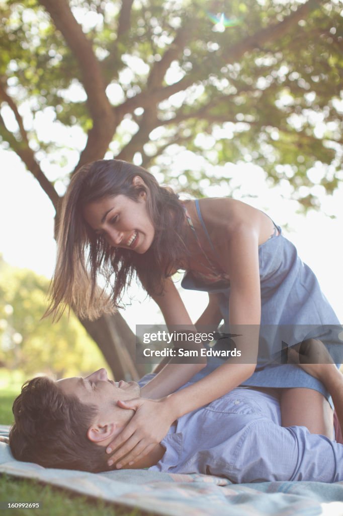 Affectionate couple on blanket in grass under tree