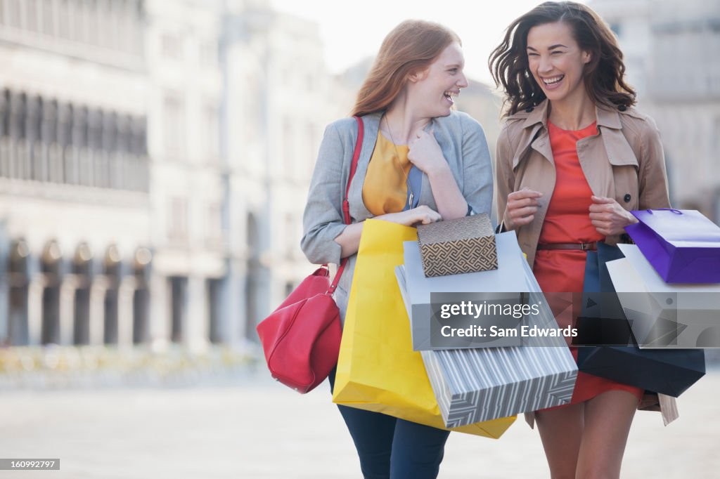 Happy women with shopping bags walking through town square