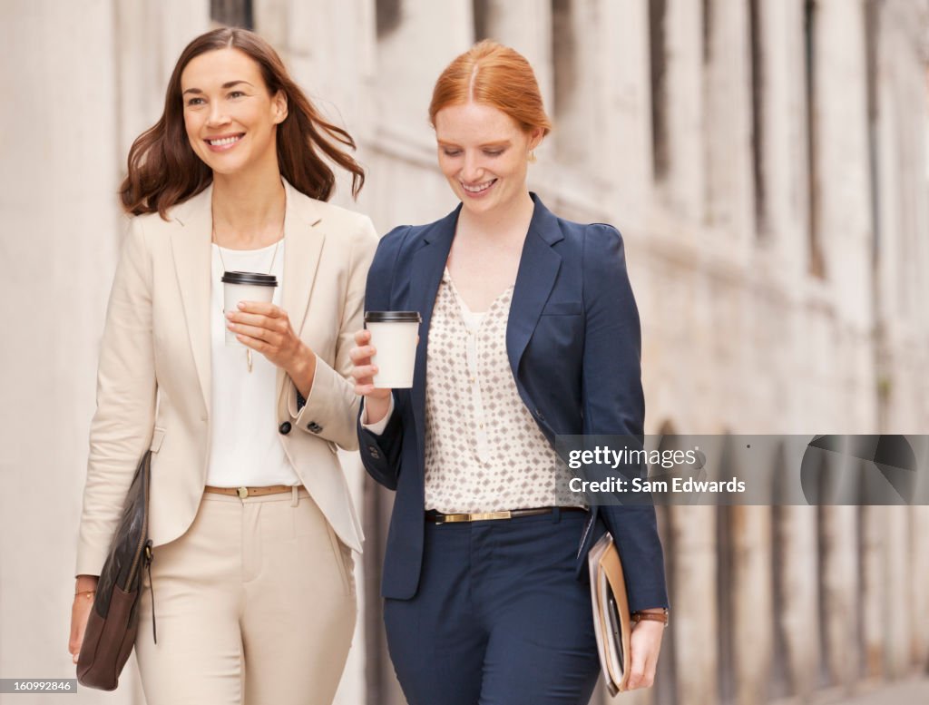 Smiling businesswomen walking with coffee