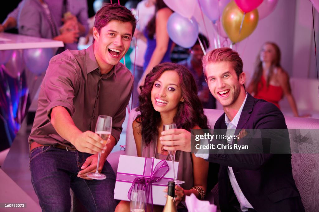 Portrait of enthusiastic friends with champagne and gift