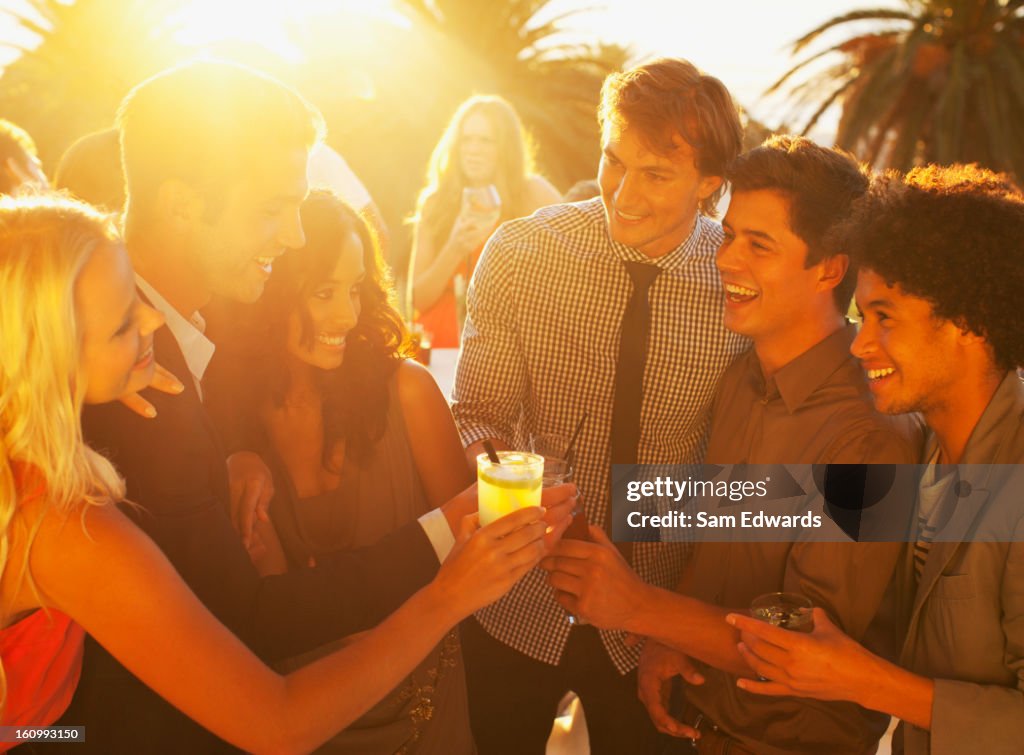 Friends toasting cocktails on sunny balcony