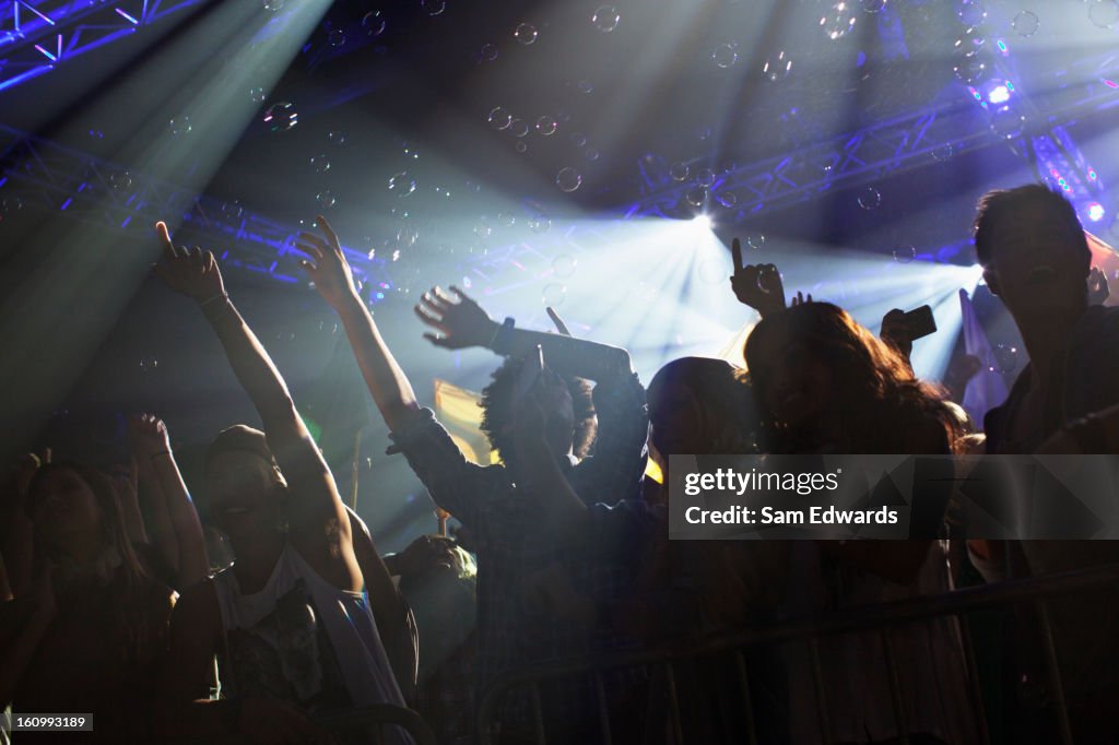 Crowd cheering with arms raised at concert