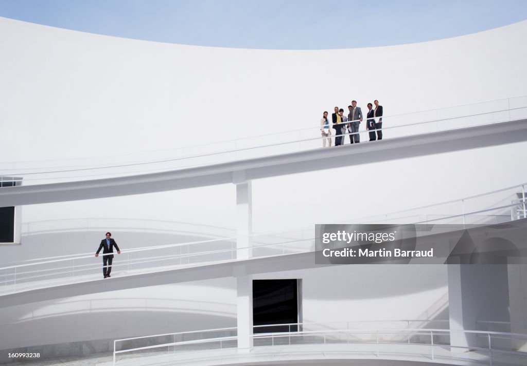 Businessman below business people on elevated walkway