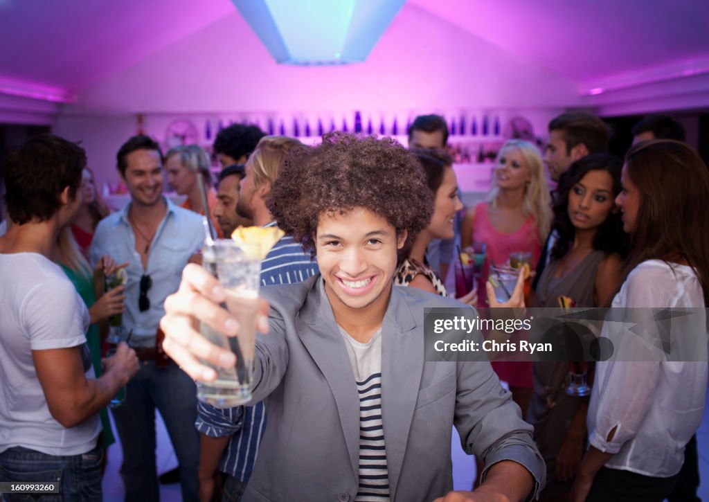 Portrait of smiling man holding cocktail at bar in nightclub