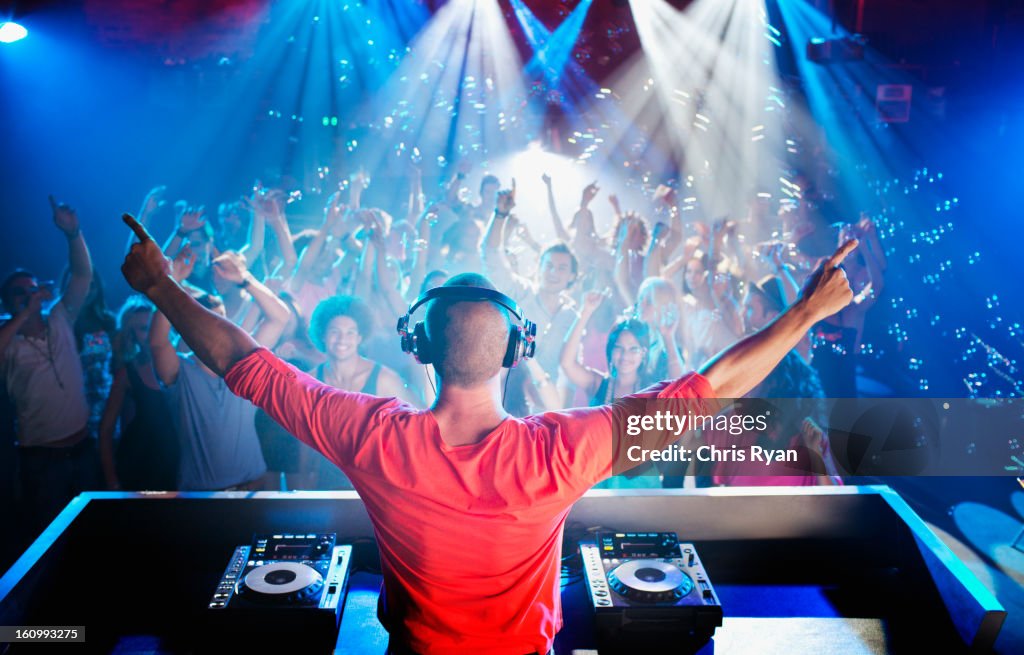 DJ con brazos estirados con vista a la pista de baile