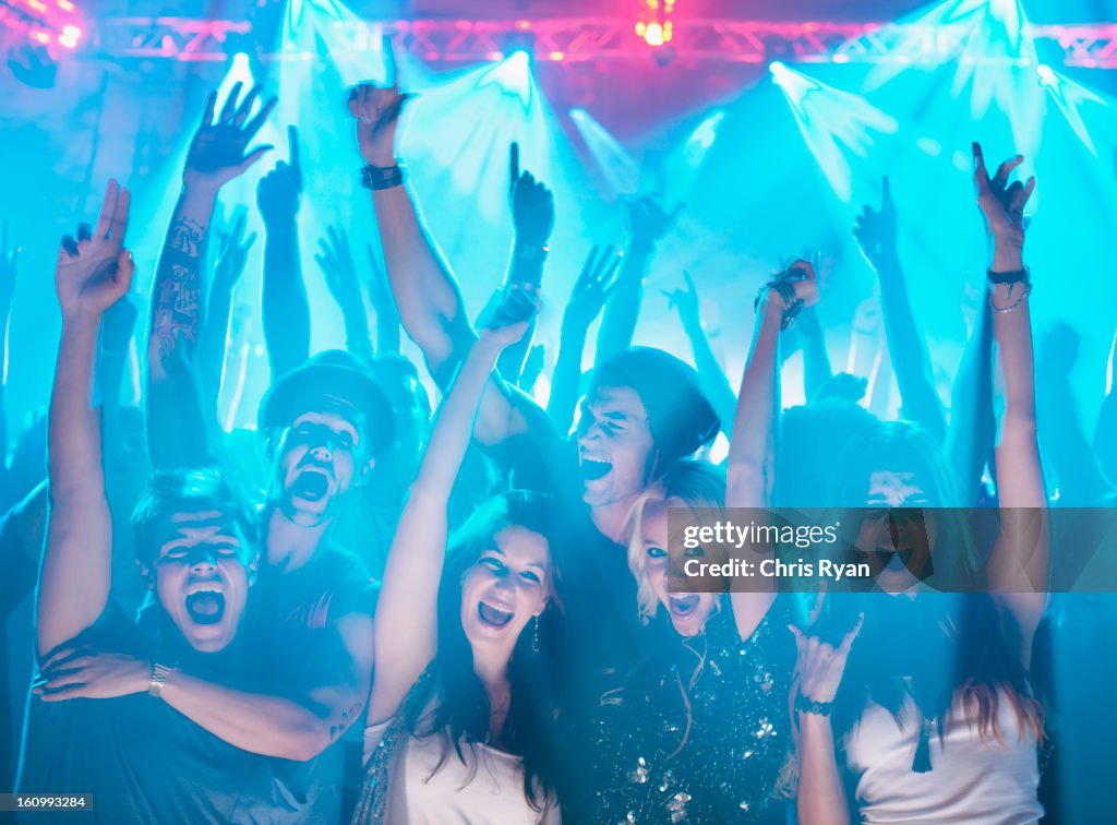 Portrait of enthusiastic crowd with arms raised at concert