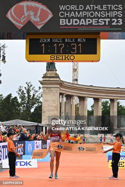 Spain's Alvaro Martin celebrates with a Spanish flag as he crosses the finish line in the men's 20km race walk final during the World Athletics...