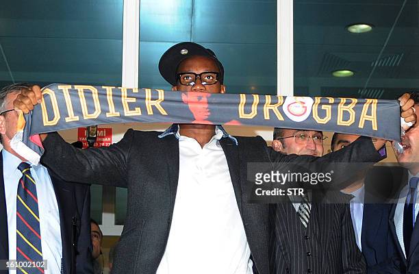 Galatasaray's football club new forward Didier Drogba from Ivory Coast presents his new team scarf as he arrives at the Ataturk airport in Istanbul,...