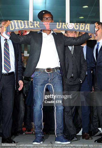 Galatasaray's football club new forward Didier Drogba from Ivory Coast presents his new team scarf as he arrives at the Ataturk airport in Istanbul,...