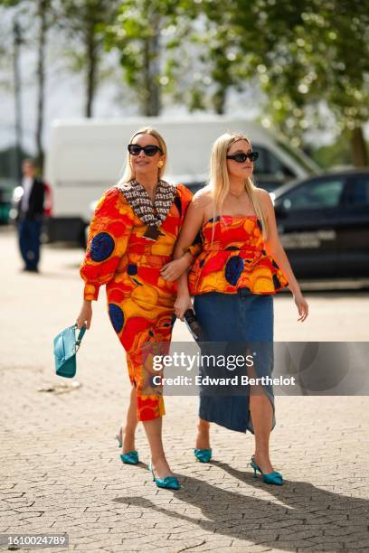 Guest wears black sunglasses, a dark brown and white latte print pattern wool pullover knot at the waist, a neon orange with yellow / navy blue print...