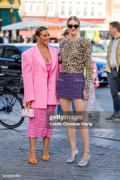 Janka Polliani wears pink oversized blazer, dress, mini bag, orange heels & Marianne Theodorsen wears animal print shirt with long sleeves, mini...