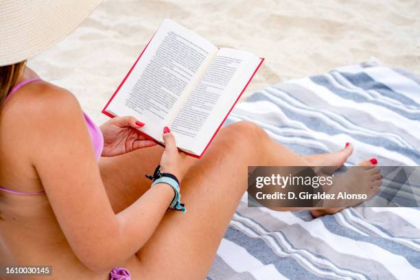 woman lying on a towel with a book at a beach. - blue white summer hat background stock pictures, royalty-free photos & images
