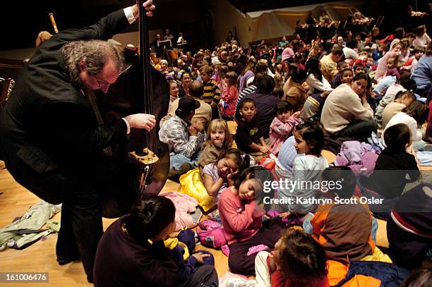 Bass player Ron<cq> Bland<cq> moves from behind his music stand and places himself within inches of a group of children who are instructed to pretend...