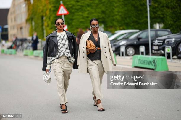 Guest wears black sunglasses, silver earrings, a beige with black checkered print pattern pullover, a black shiny leather zipper jacket, beige suit...
