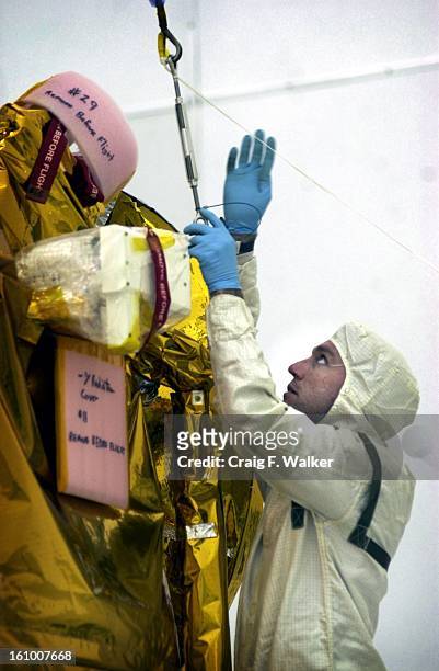 Lockheed Martin Spacecraft technician Terry Campmann attatches a crane to the Mars 2001 Odessey prepring to place the craft on an assembly dolly in a...