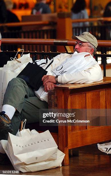 Bob Downing of Ogallala, Nebraska is covered with bags and purses as he sits in the atrium of ParK Meadows Mall in Littleton on Thursday, December...