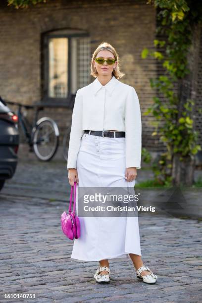 Hollie Mercedes Peters wears white skirt, button shirt, pink bag, shoes outside Ganni during the Copenhagen Fashion Week Spring/Summer 2024 on August...