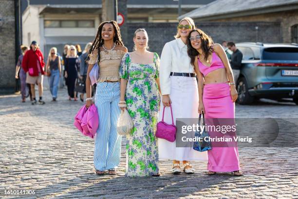 Fia Hamelijnck wears blue white striped pants, beige blouse & Yara Michels wears green dress with print & Hollie Mercedes Peters wears white button...