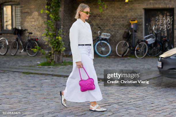 Hollie Mercedes Peters wears white skirt, button shirt, pink bag, shoes outside Ganni during the Copenhagen Fashion Week Spring/Summer 2024 on August...