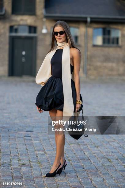 Nina Sandbech wears black skirt, body, creme white scarf, Alaia bag, heels outside Ganni during the Copenhagen Fashion Week Spring/Summer 2024 on...