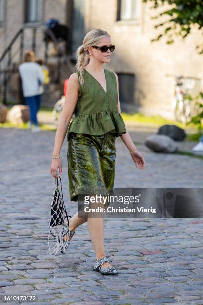 Guest wears green sleeveless shirt, shorts, net bag outside Ganni during the Copenhagen Fashion Week Spring/Summer 2024 on August 10, 2023 in...