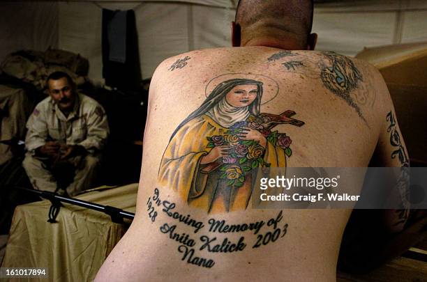 Support Squadron -SPC Martin Kalick, right, of Mt. Ephrain, NJ, displays the tattoo of Saint Theresa on his back while SPC while talking with SPC...