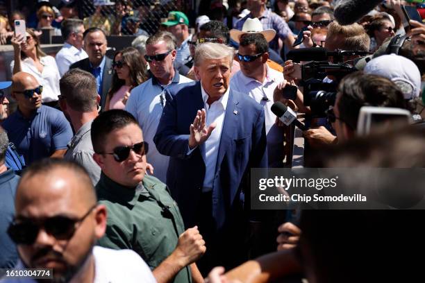 Surrounded by campaign staff and members of the U.S. Secret Service, Former U.S. President Donald Trump waves to supporters as he visits the Iowa...