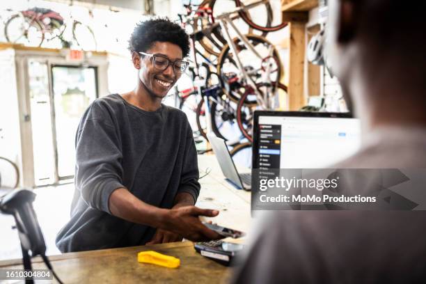 customer making using contactless payment at bike shop counter - sportgeschäft stock-fotos und bilder