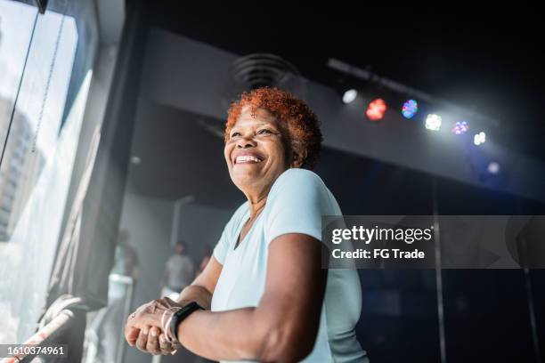 contemplative senior woman looking through the window at dance studio - backstage view stock pictures, royalty-free photos & images