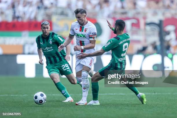 Ermedin Demirovic of FC Augsburg and Franck Honorat of Borussia Moenchengladbach battle for the ball during the Bundesliga match between FC Augsburg...