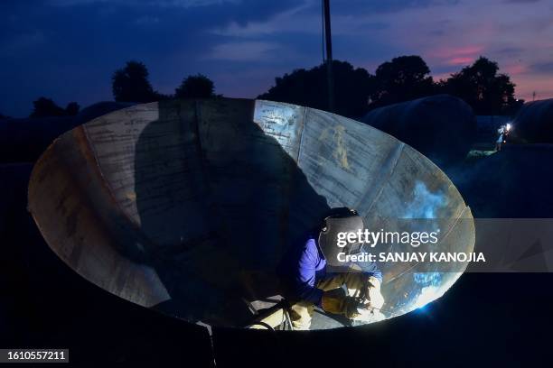 Metalsmith welds a pontoon bridge at a workshop in Prayagraj on August 19, 2023.