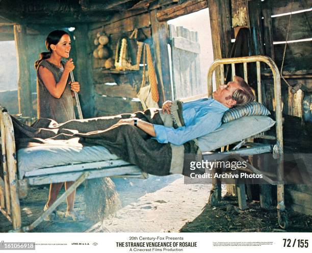 Bonnie Bedelia sweeping the floor as Anthony Zerbe lays in bed in a scene from the film 'The Strange Vengeance Of Rosalie', 1972.