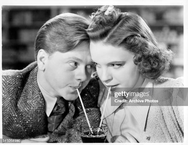 Mickey Rooney and Judy Garland sharing a soda together as they stare into one an others eyes in a scene from the film 'Babes In Arms' which was...