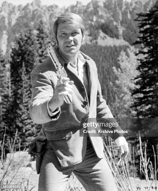 Glen Campbell holds a gun in a scene from the film 'True Grit', 1969.